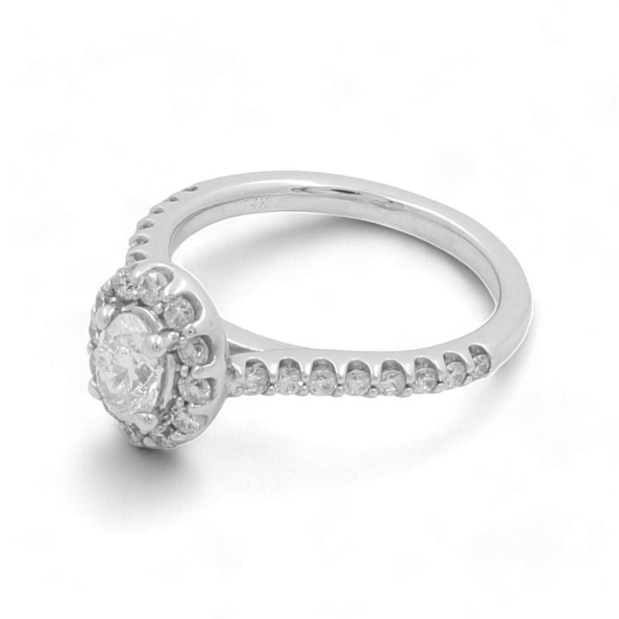 The 14K White Gold Bridal Woman Ring with Diamonds by Miral Jewelry showcases a central round diamond encircled by smaller diamonds, with additional small diamonds embellishing the band.