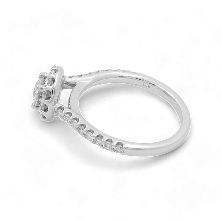 A 14K White Gold Bridal Woman Ring from Miral Jewelry, featuring multiple small diamonds set along the band and a larger central gemstone held by four prongs.