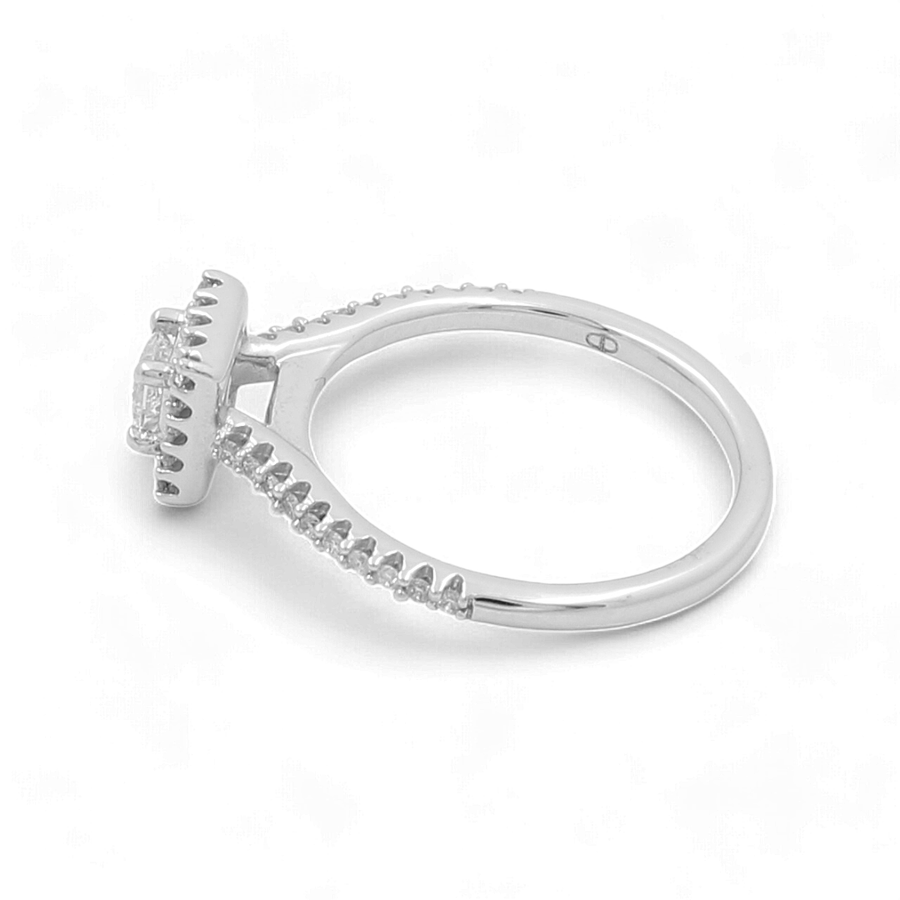 This exquisite 14K white gold bridal ring from Miral Jewelry features a prong-set central gemstone, elegantly accented with small diamonds lining the band.