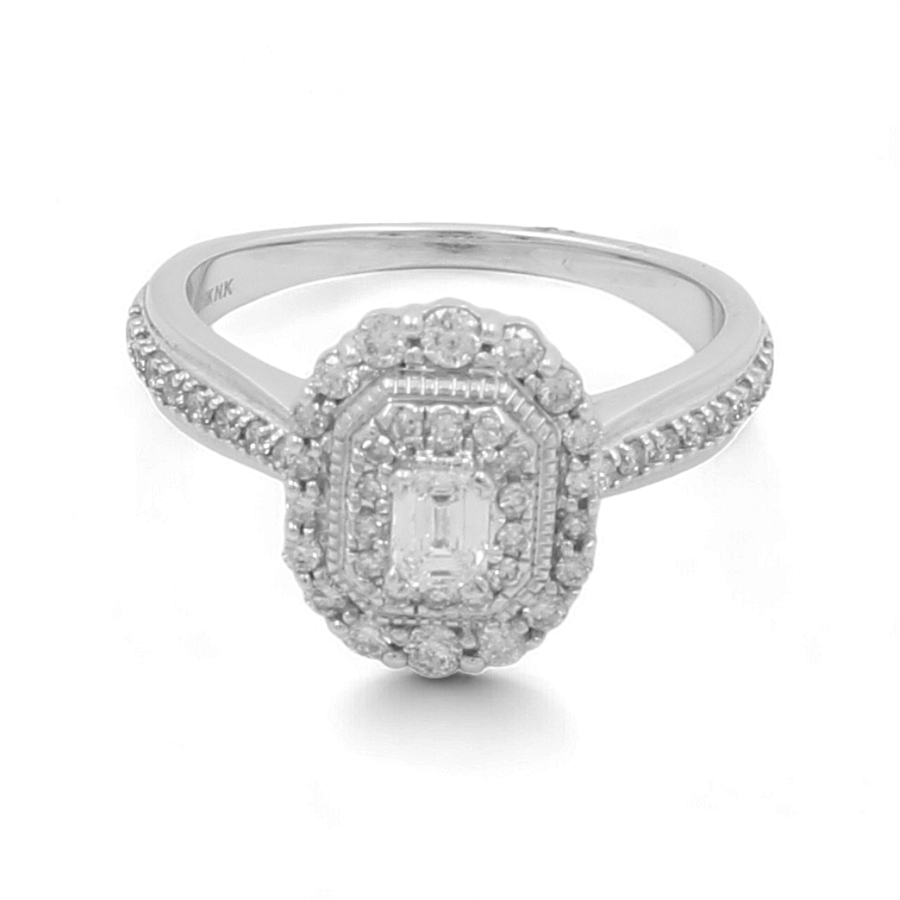 The 10K White Gold Bridal Woman Ring with Diamonds by Miral Jewelry features a striking rectangular-cut white gemstone surrounded by smaller round gems, along with additional round gems encrusted along the band; this exquisite piece is perfect as part of a bridal set.