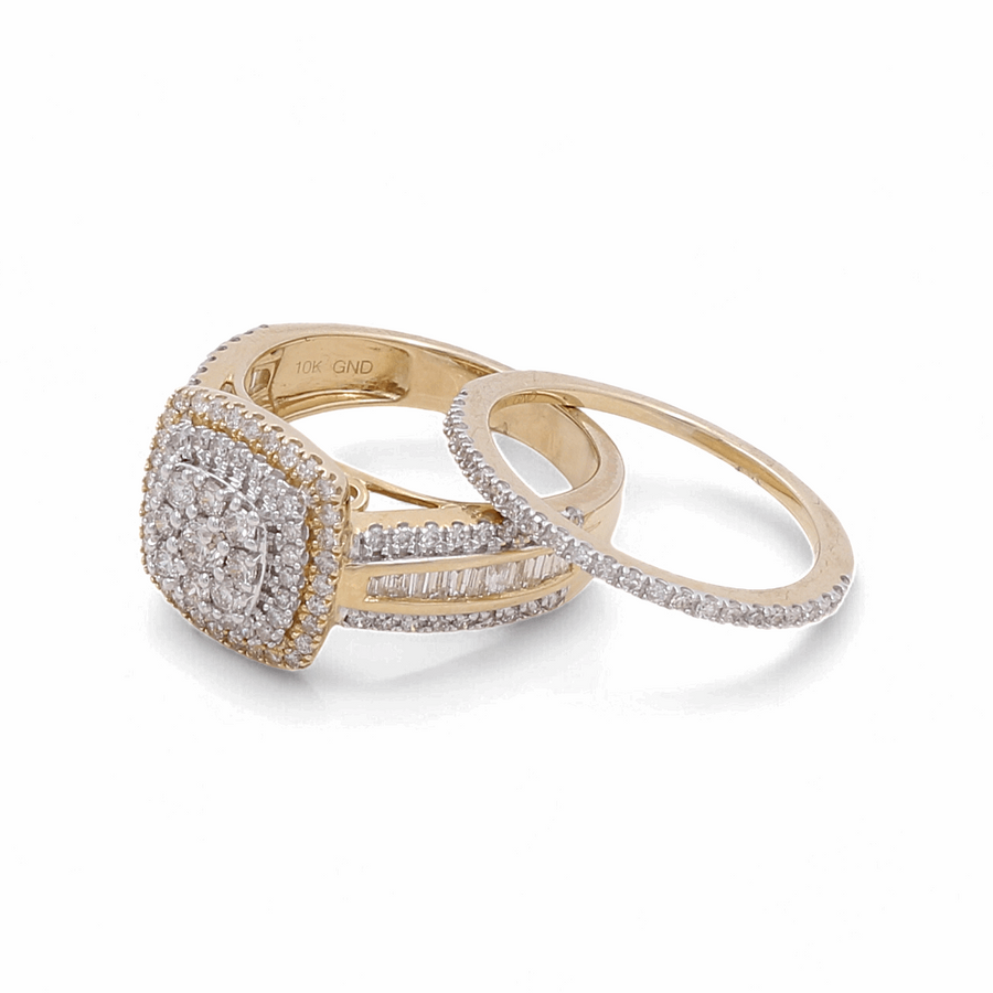 The 10K Yellow Gold Bridal Woman Ring with Diamonds by Miral Jewelry is a stunning set of two rings. One ring showcases a breathtaking cluster of diamonds in a rectangular setting, while the other features an elegantly simple band design adorned with small diamonds. This exquisite duo is perfect for a woman's special day.