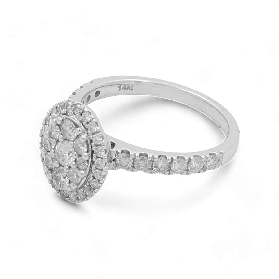 The 14K White Gold Bridal Woman Ring with Diamonds by Miral Jewelry is a luxurious piece, showcasing a central round cluster of small diamonds encircled by a halo of more diamonds, and additional diamonds elegantly set along the band.