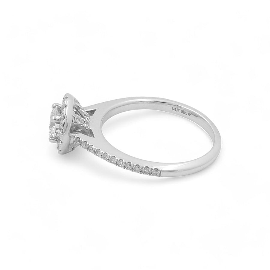 The Miral Jewelry 14K White Gold Women's Contemporary Engagement Ring is a stunning piece, featuring a central round diamond encircled by smaller round diamonds encrusted along the band, with the elegant "14K" marking on the band.