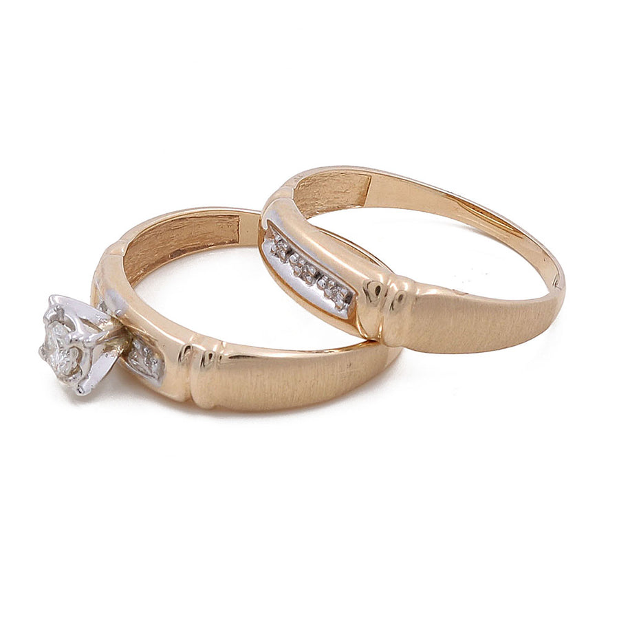 Two bridal rings from Miral Jewelry, crafted in 14K yellow gold and adorned with stunning diamond accents, with one showcasing a central diamond in a prong setting.