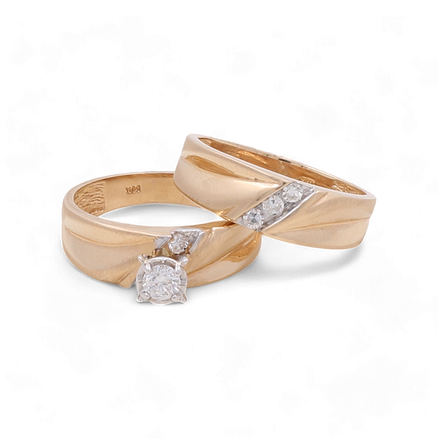 Two exquisite rings from Miral Jewelry, both crafted in 14K yellow gold, feature diamond accents. One ring showcases a larger central diamond, while the other boasts three smaller diamonds set in an elegant diagonal pattern. These 14K yellow gold bridal rings are ideal for a timeless and beautiful commitment symbol.