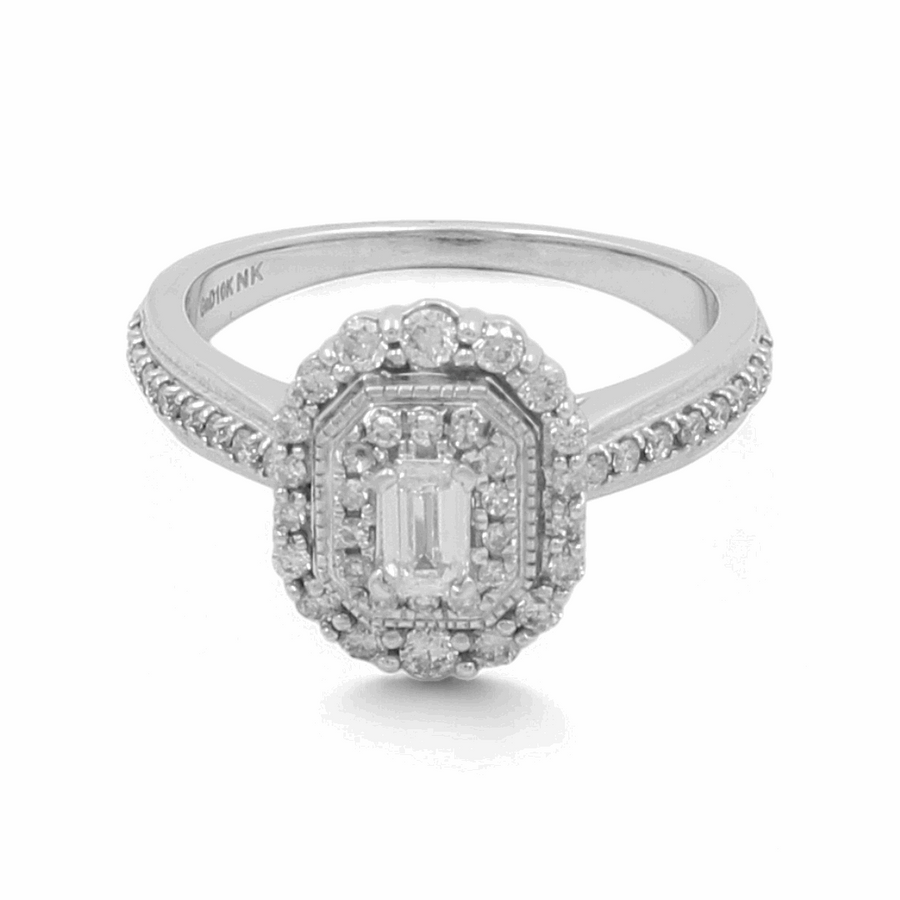 The 10K White Gold Bridal Woman Ring from Miral Jewelry features a central emerald-cut diamond surrounded by a double halo of smaller diamonds and additional diamonds along the band, offering an elegance that mirrors the beauty of a classic bridal ring.