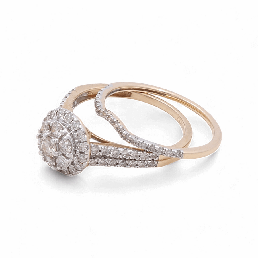 The 14K Yellow Gold Bridal Woman Ring with Diamonds by Miral Jewelry showcases an intertwined design and a circular diamond cluster centerpiece, elegantly adorned with small round diamonds.