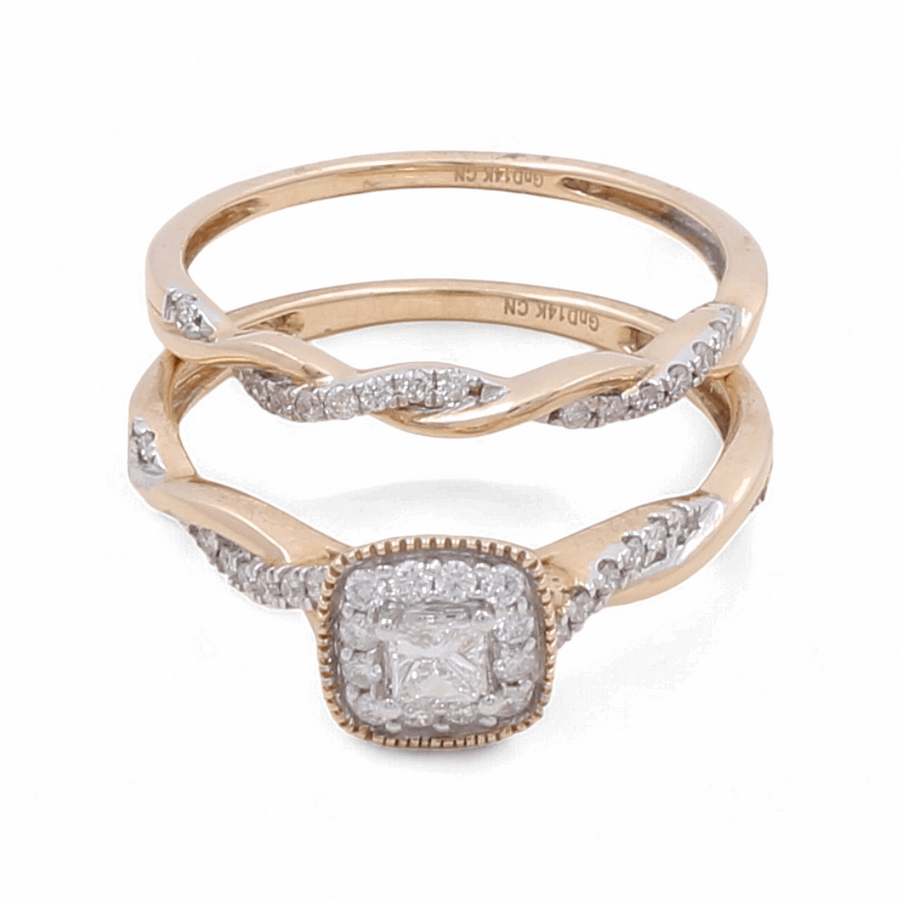 The 14K Yellow Gold Bridal Woman Ring with Diamonds from Miral Jewelry is a stunning set of two rings. One ring features a square-shaped diamond centerpiece, while the other showcases an elegant twisted band design. This exquisite wedding ring set perfectly embodies elegance and timeless beauty.