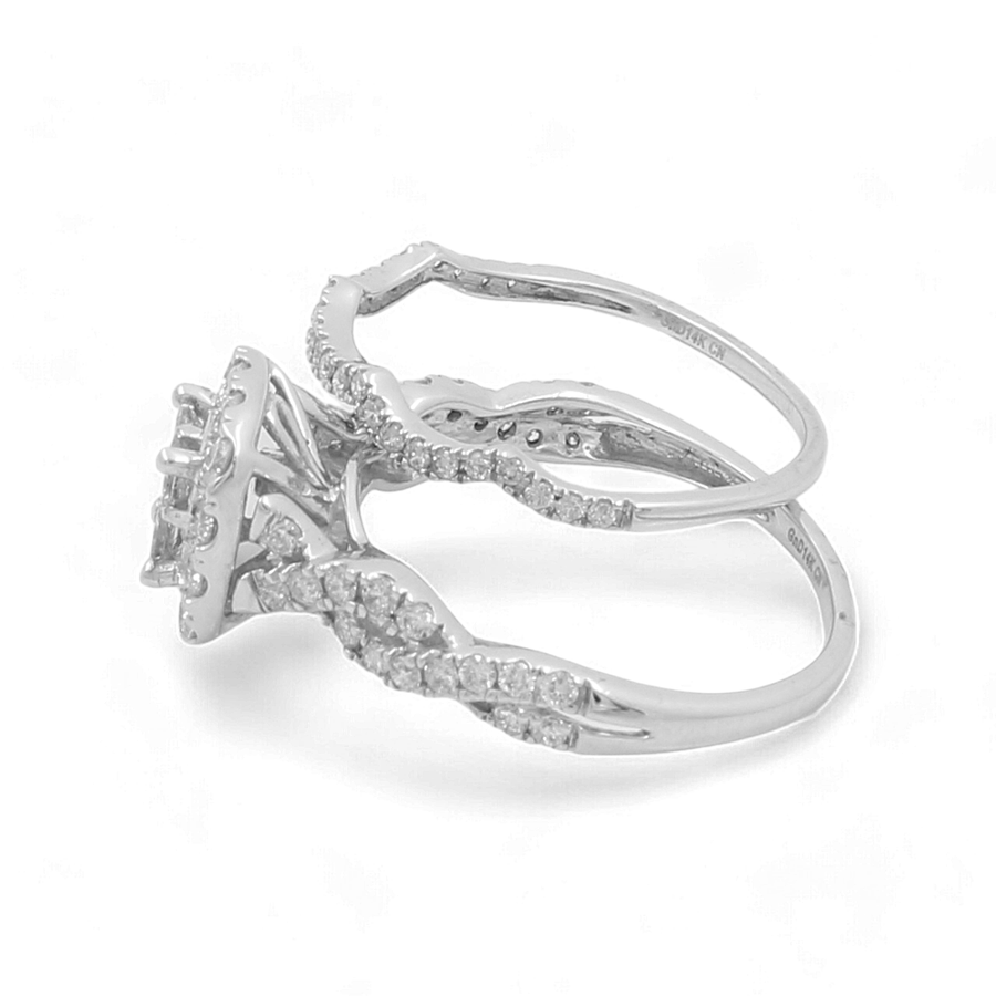 The 14K White Gold Bridal Woman Ring with Diamonds by Miral Jewelry boasts an intricately twisted band design and a central setting adorned with multiple small diamonds.
