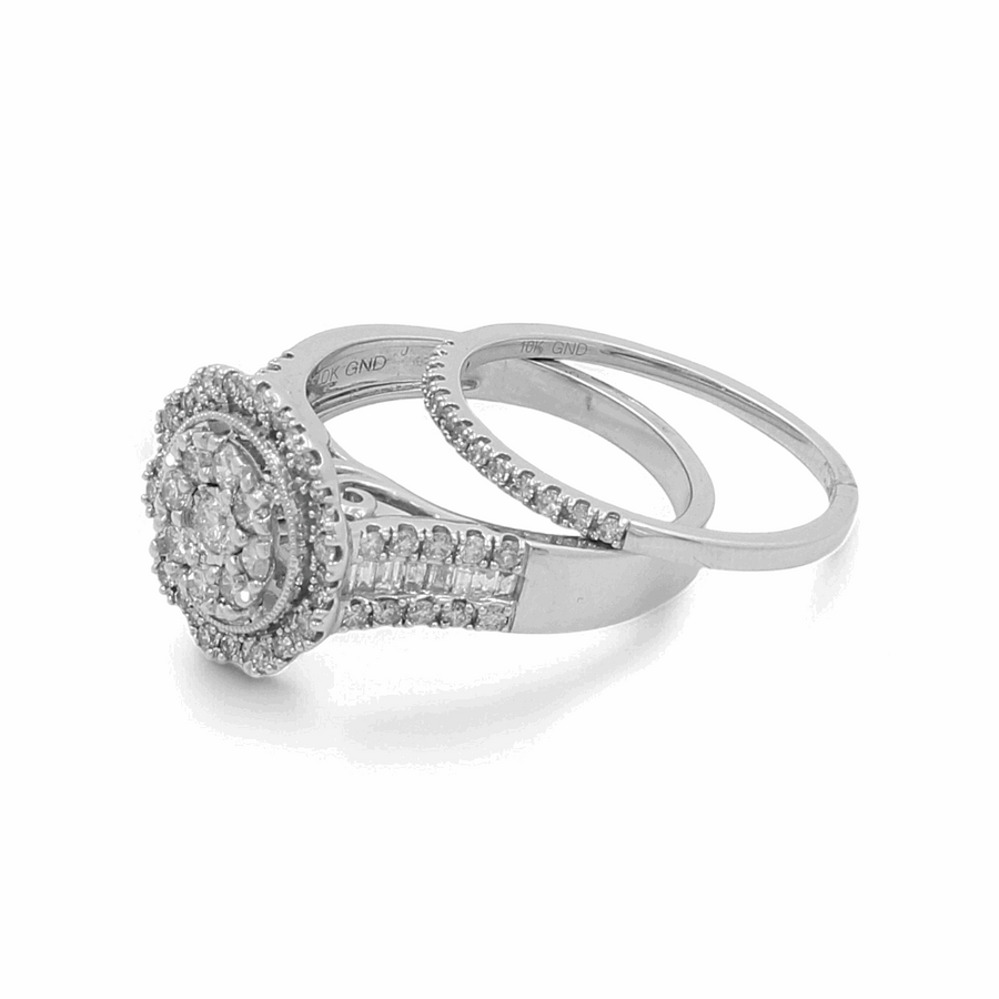 The 10K White Gold Bridal Woman Ring with Diamonds by Miral Jewelry features a central round diamond encircled by a halo of smaller diamonds, paired with a matching diamond-studded wedding band. This exquisite set, crafted in 10K white gold, symbolizes everlasting love and elegance.