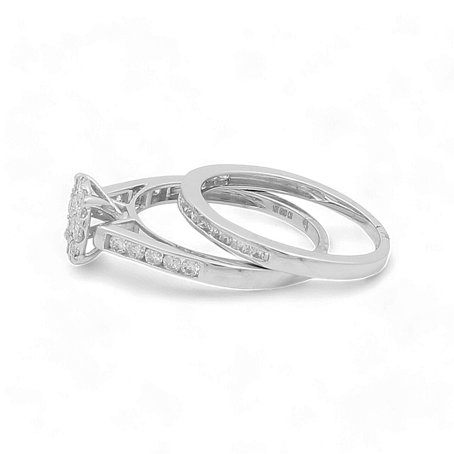 The 10K White Gold Bridal Woman Ring with Diamonds by Miral Jewelry features two interlocking rings: one adorned with a solitaire diamond and smaller diamonds along the band, and the other a plain band with inlaid diamonds, making it perfect for the bridal woman.