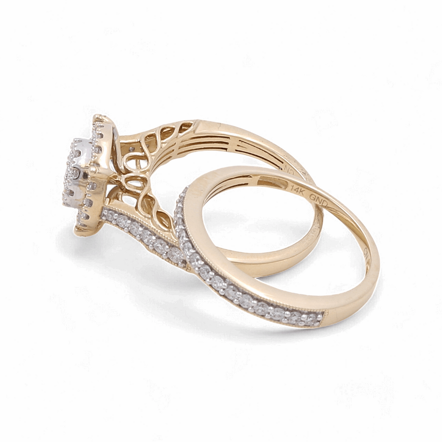 The 14K yellow gold bridal woman ring with diamonds from Miral Jewelry, featuring a large central stone and a matching wedding band both embellished with small diamonds, are displayed side by side on a white background.