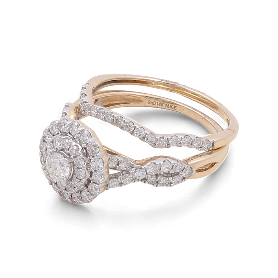 A dazzling 14K yellow gold bridal woman's ring from Miral Jewelry, showcasing a large round diamond encircled by smaller diamonds in an exquisite floral design. The double bands of the ring are set with additional sparkling diamonds.