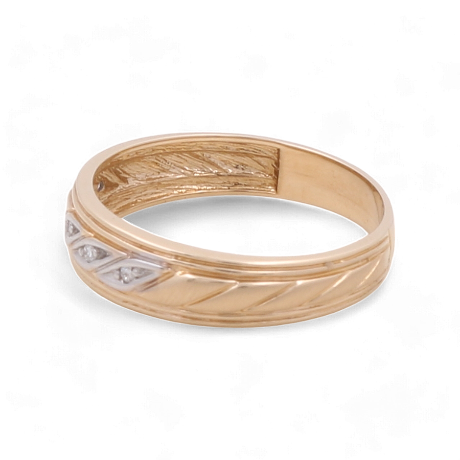 A men's bridal ring from Miral Jewelry, crafted meticulously from 14K yellow gold, featuring a patterned design and three small diamonds elegantly set in a line on one side.