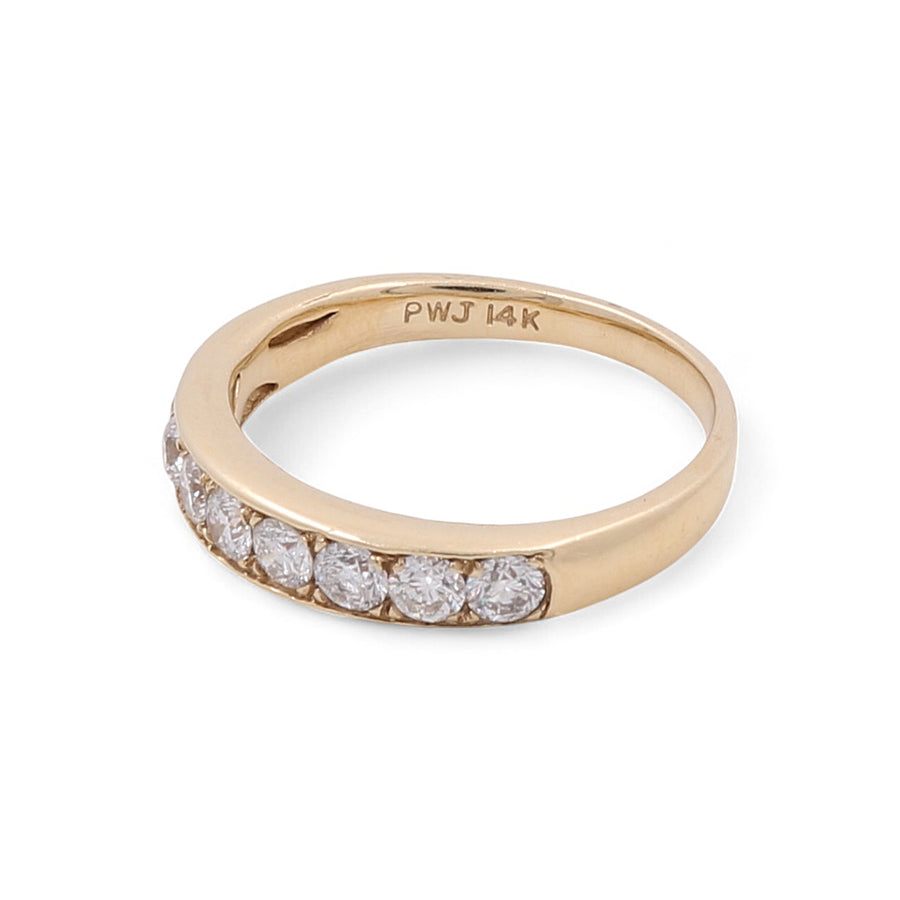 The 14K Yellow Gold Wedding Single Band Women's Ring by Miral Jewelry features a single row of eight small, round diamonds embedded on one side and is marked "PWJ 14K" on the inner band.