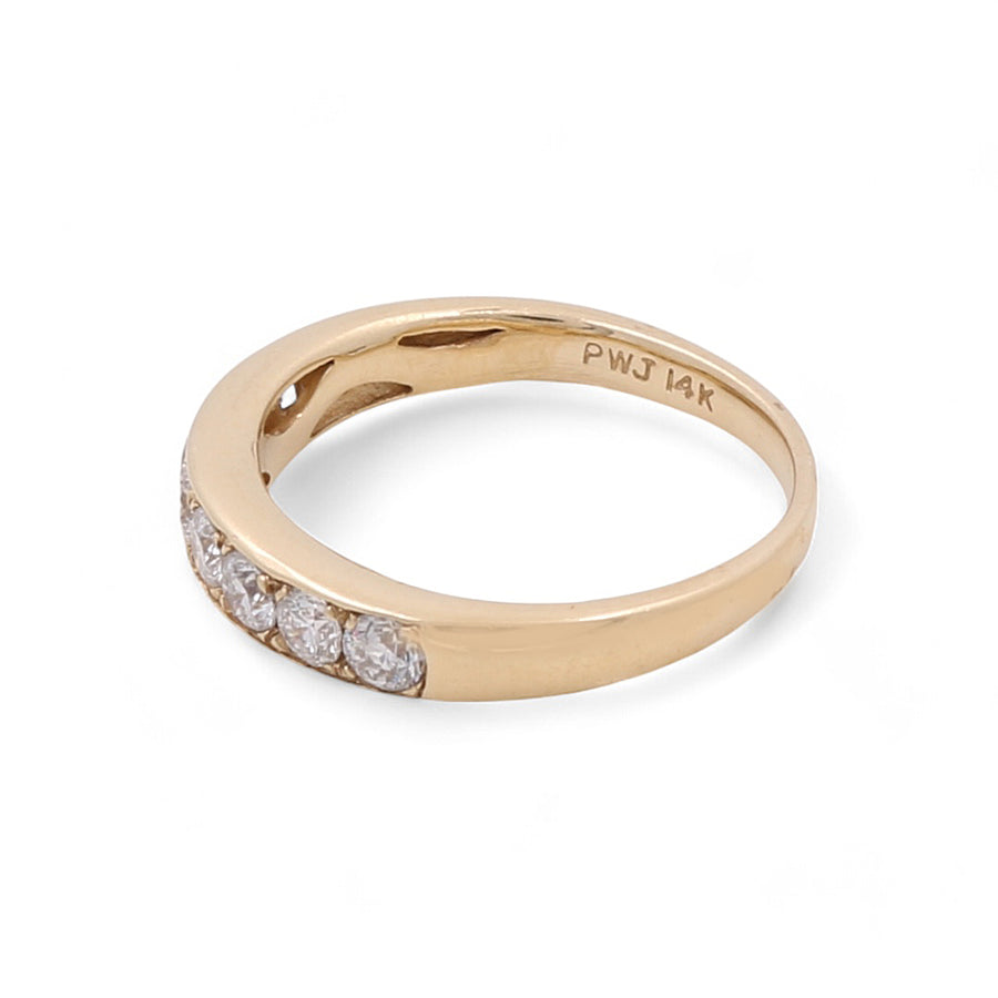 The 14K Yellow Gold Wedding Single Band Women's Ring by Miral Jewelry features a row of channel-set diamonds embedded on one side, with an engraving on the inner band that reads "PWJ 14K.