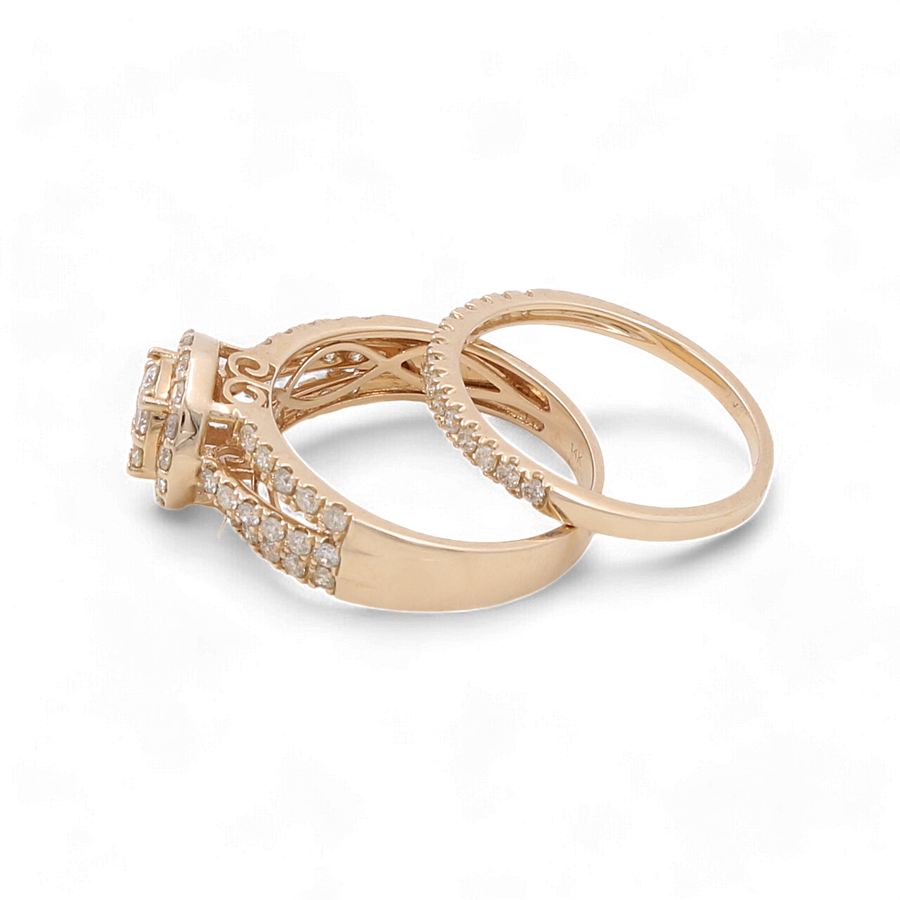 On a white background, two stunning pieces of Miral Jewelry stand out: the 14K Yellow Gold Bridal Woman Ring with Diamonds features a wedding band adorned with small diamonds and an engagement ring boasting a larger central stone complemented by intricate detailing. Perfect for the discerning bridal woman.