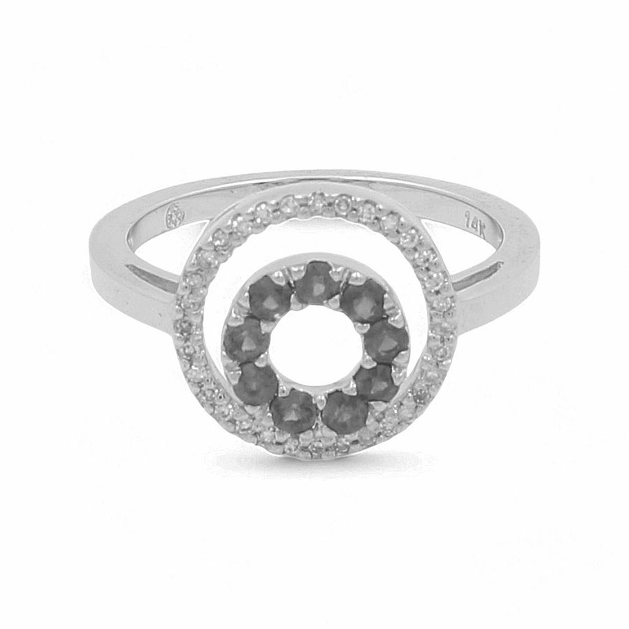 Introducing the "14K White Gold Fashion Diamond Woman Ring" by Miral Jewelry—a stunning silver ring with a circular design, accented with black stones at the center and encircled by smaller clear stones. It's perfect for anyone looking to make a fashion statement.