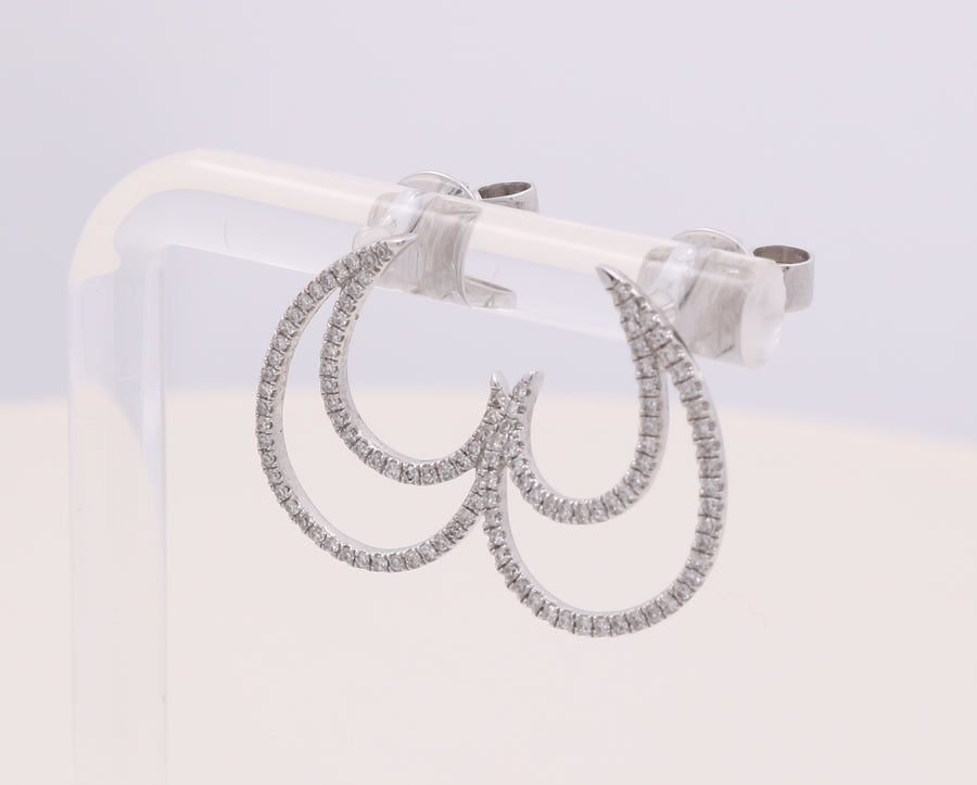 A pair of Miral Jewelry's 14K White Gold Fashion Diamond Women Earring Drops, adorned with small, sparkling clear stones, is displayed on a transparent stand, exuding the elegance of the Fashion Diamond collection.