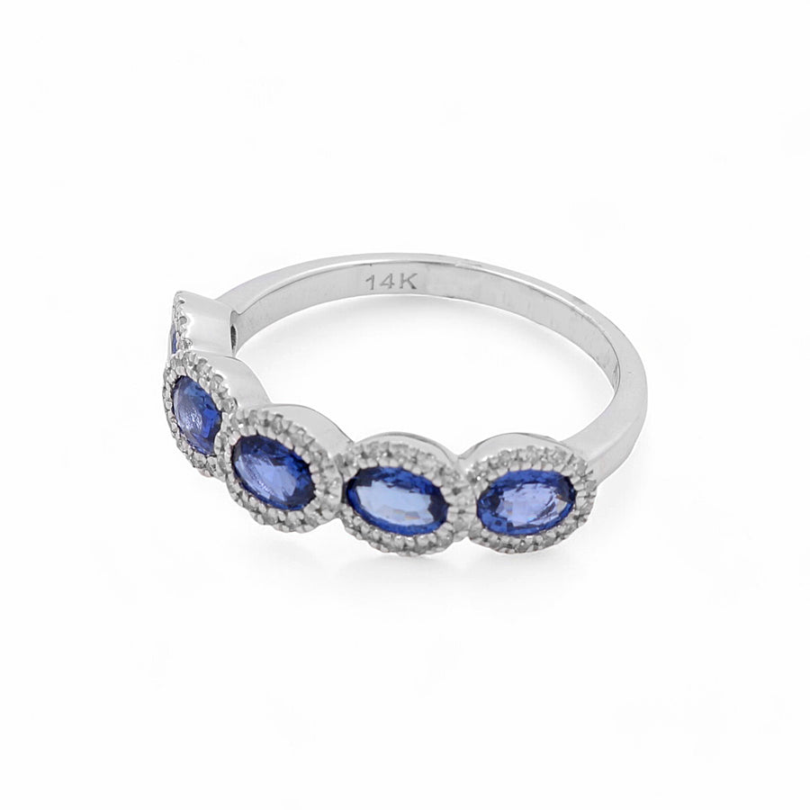 A stunning women's ring crafted in 14K white gold by Miral Jewelry, featuring four blue oval sapphires each elegantly surrounded by small clear stones.