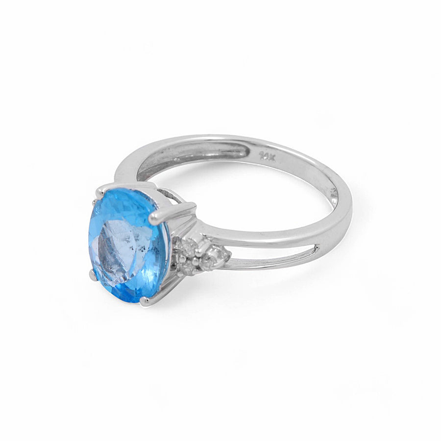 A 14K white gold ring featuring an oval blue topaz center stone, flanked by two smaller diamonds on each side, exemplifying contemporary diamond elegance from Miral Jewelry.