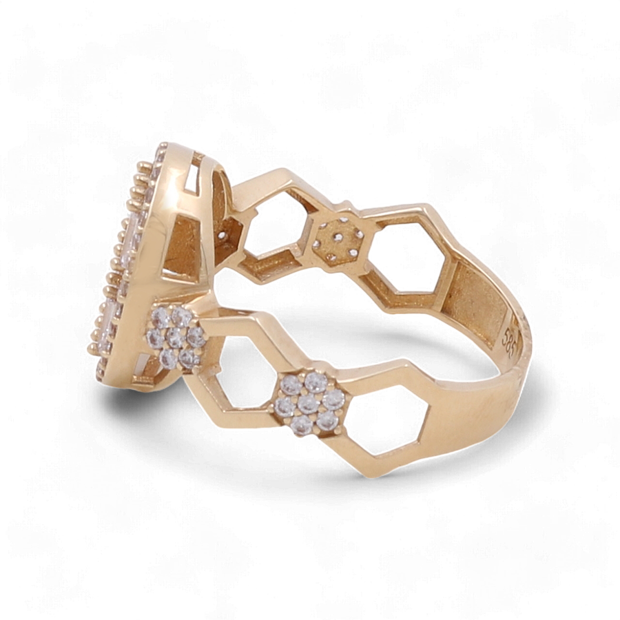 The 14K Yellow Gold Engagement Women's Ring by Miral Jewelry, featuring a hexagonal pattern and adorned with small clear cubic zirconia stones, viewed from an angle.