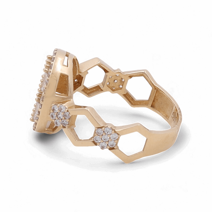 The 14K Yellow Gold Engagement Women's Ring by Miral Jewelry, featuring a hexagonal pattern and adorned with small clear cubic zirconia stones, viewed from an angle.