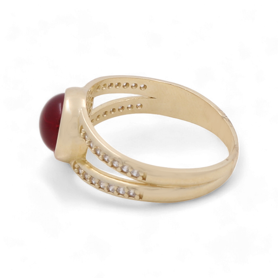 The 14K Yellow Gold Fashion Evil Eye with Zirconias Women's Ring by Miral Jewelry exudes elegance with its red gemstone and small round cut zirconias along the band.