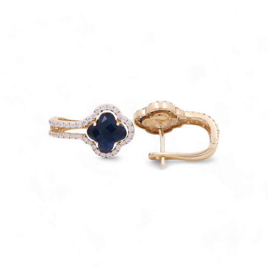 A pair of Miral Jewelry's 14K Yellow Gold Blue Stone Huggie Women's Earrings with Cz, featuring a four-leaf clover shape with a dark blue center stone surrounded by small clear stones, displayed against a white background—perfect for women's fashion.