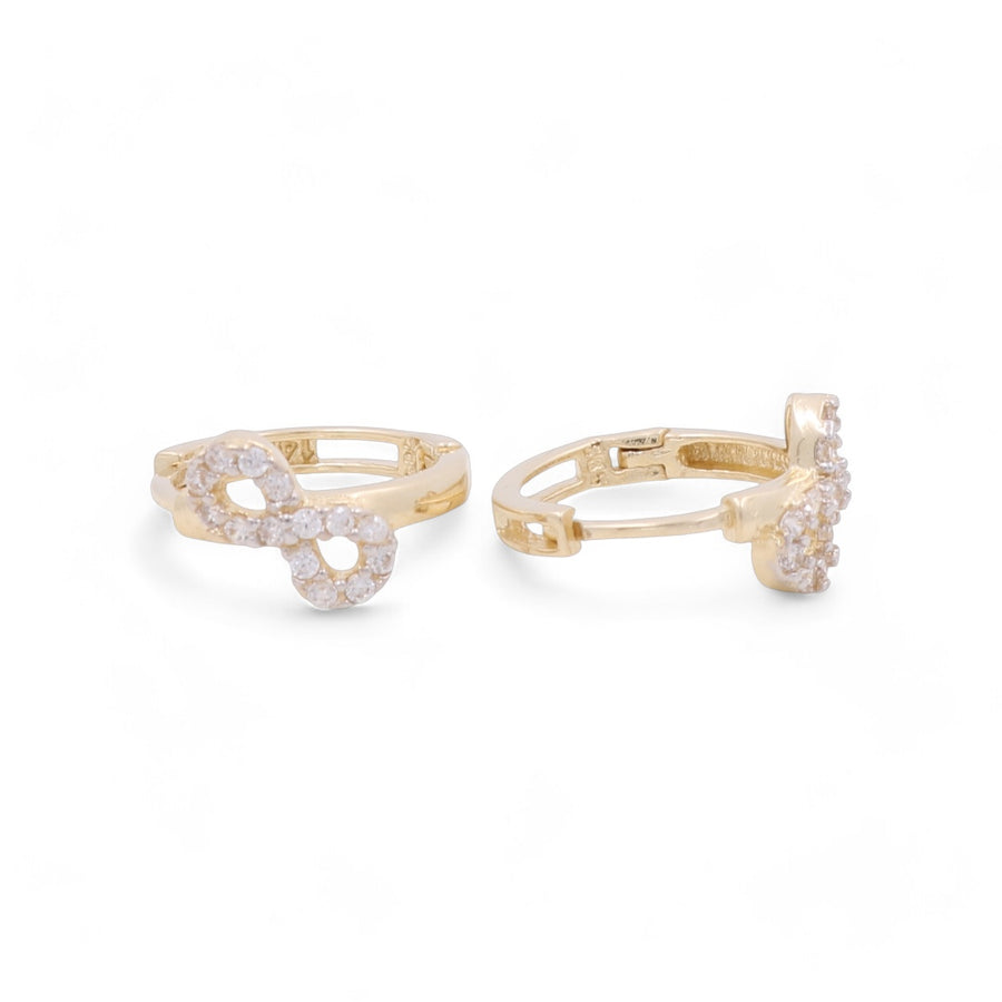 A pair of gold-tone rings with a knot design, adorned with small, sparkling stones, reminiscent of Miral Jewelry's 14K Yellow Gold Small Hoop Women's Earrings.