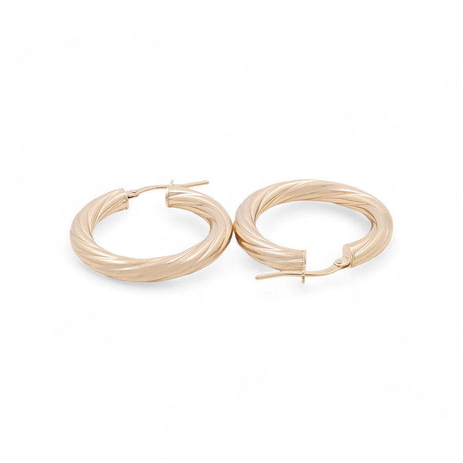 Miral Jewelry's 14K Yellow Gold Hoop Earrings feature a twisted design and hinged clasps, exuding timeless beauty and sophistication against a white background.