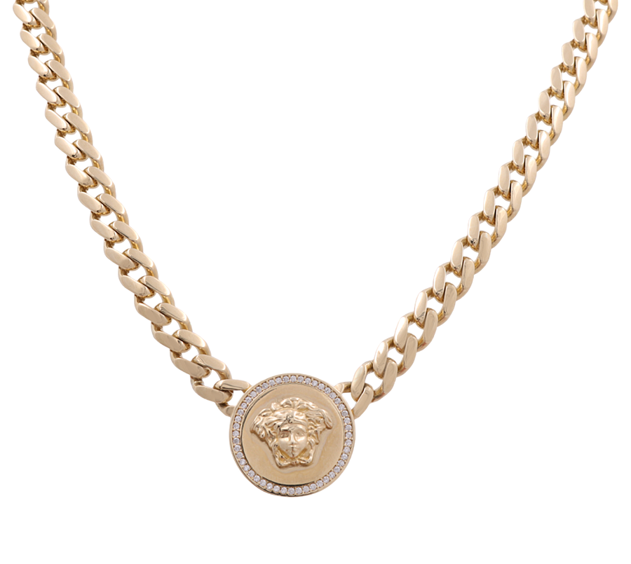 The 14K Yellow Gold Cuban Link Face Necklace by Miral Jewelry features a pendant with a relief of a face and an outer ring encrusted with small colorful stones.