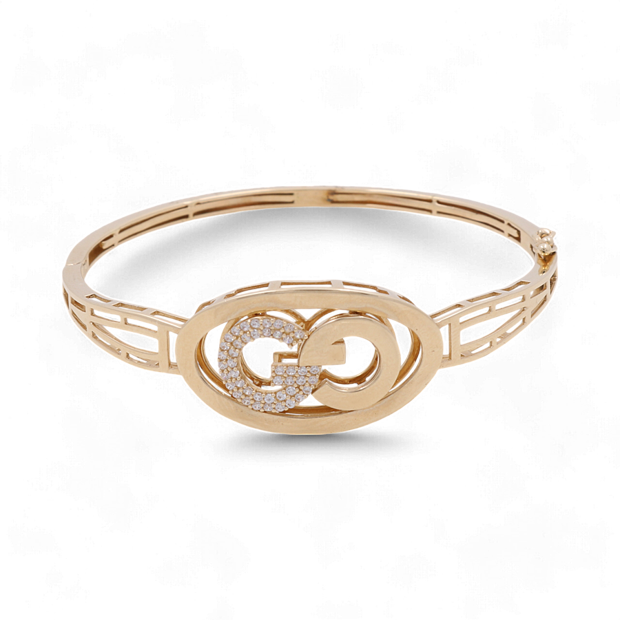 Introducing the Miral Jewelry 14K Yellow Gold Fashion Bangle Bracelet, a chic accessory featuring an interlocking double "G" logo at its center adorned with small diamonds. This fashionable bracelet boasts a band with a cut-out geometric design, making it the perfect stylish addition to any outfit.