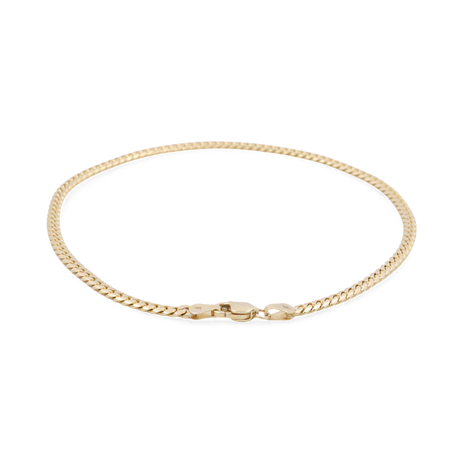 A delicate 14K yellow gold Cuban link ankle bracelet from Miral Jewelry, featuring a thin chain and a clasp, echoing the elegance of fine jewelry.