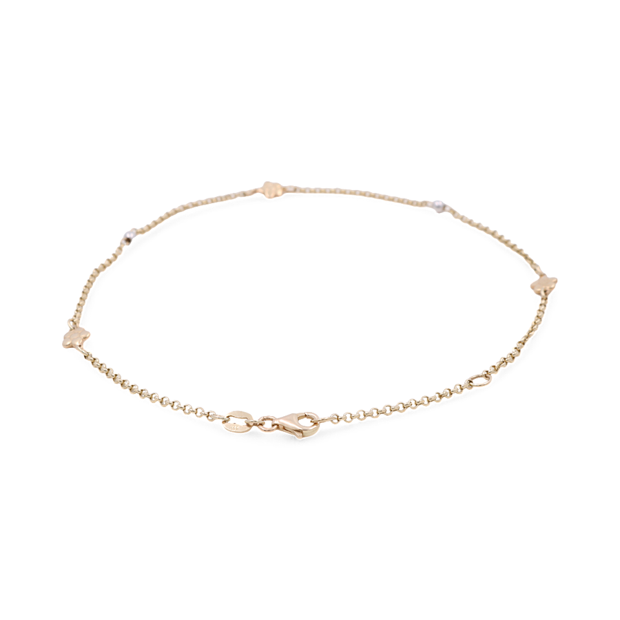 Close-up of a delicate Miral Jewelry Two Tone White and Yellow Gold 14k Women's Fashion Ankle Bracelet adorned with small heart-shaped accents, featuring a secure lobster clasp closure. This exquisite piece of fashion jewelry adds a touch of elegance to any outfit.