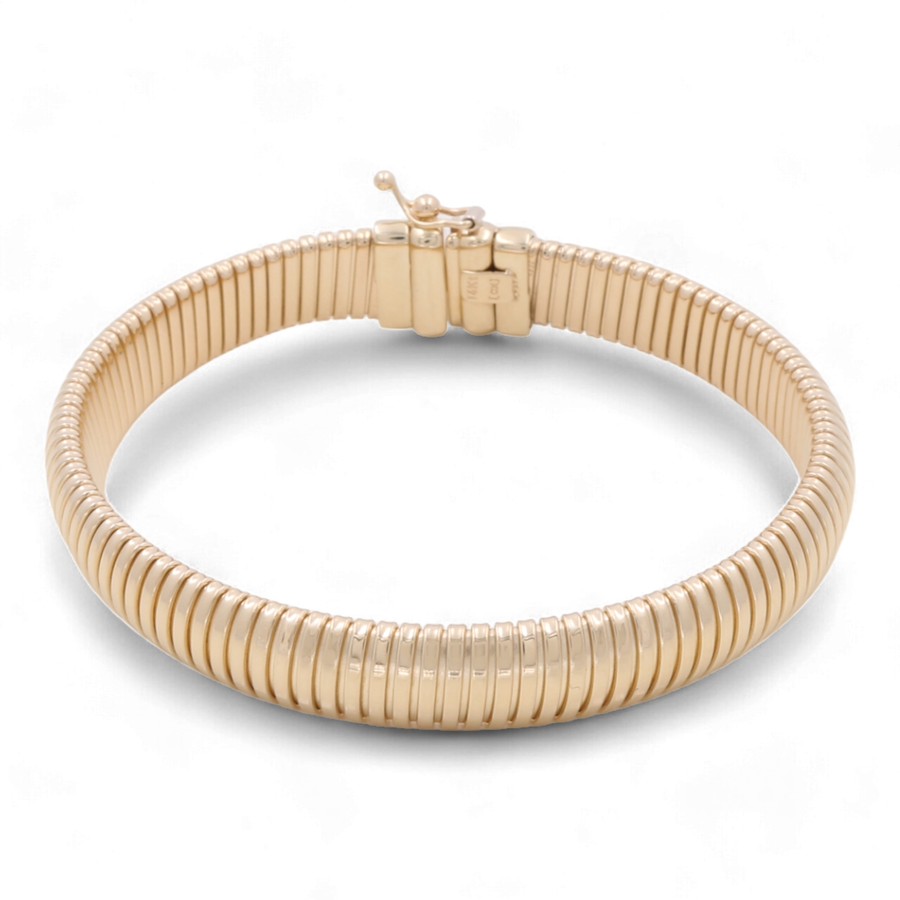 The 14K Yellow Gold Fashion Ridge Bangle by Miral Jewelry features a seamless design with a clasp closure, making it the perfect luxury accessory for any occasion.