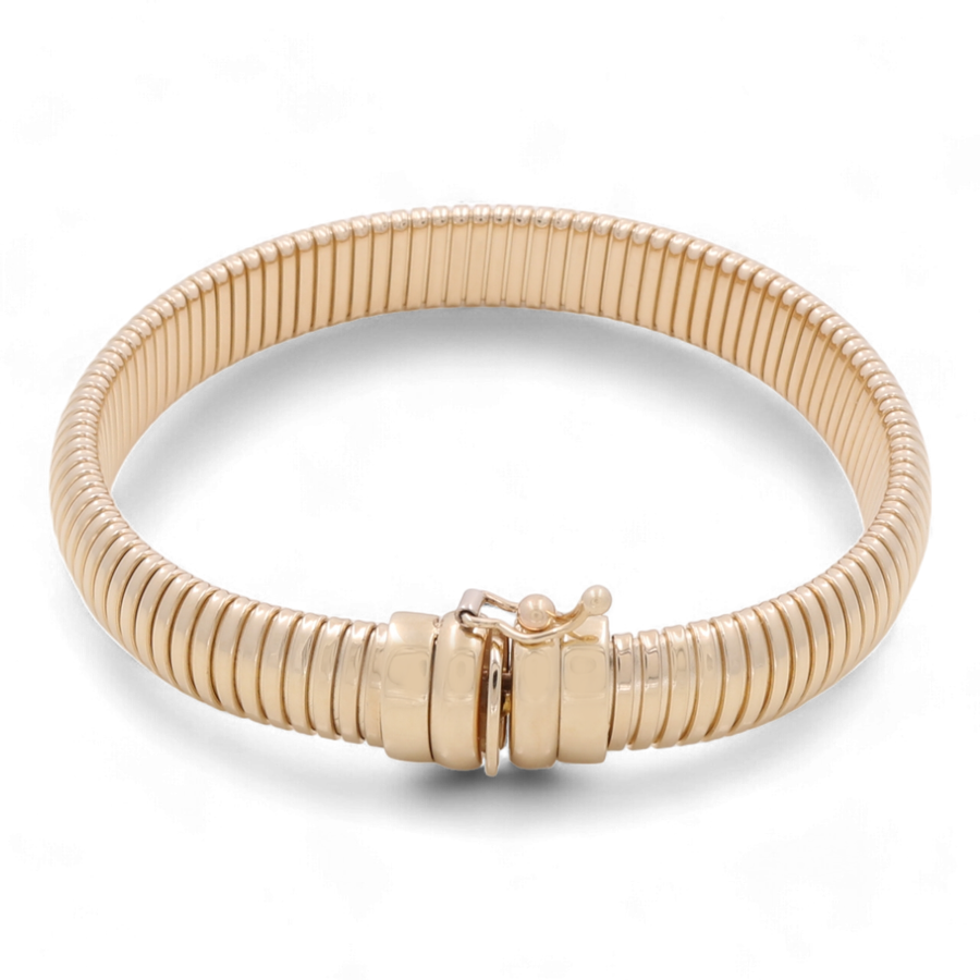 The 14K Yellow Gold Fashion Ridge Bangle by Miral Jewelry features a coiled design with a clasp fastening and flexible, ribbed texture throughout its circular structure. This luxury accessory crafted in 14K yellow gold adds an elegant touch to any outfit.