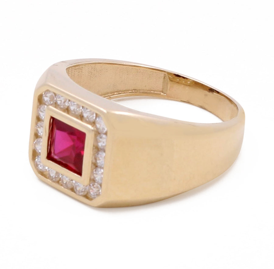 The Miral Jewelry 14K Yellow Gold Men's Ruby Ring with Cubic Zirconias, featuring a central square red gemstone surrounded by small clear cubic zirconias set in a raised square bezel, epitomizes luxurious jewelry.