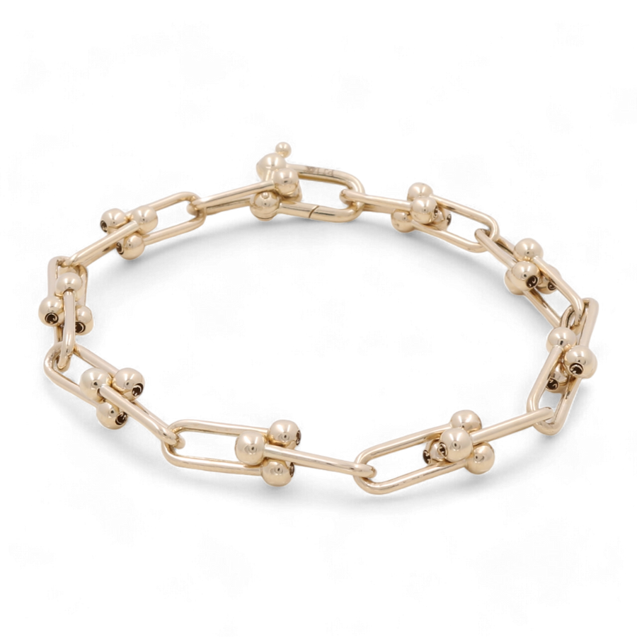 The 14K Yellow Gold Fashion Link Bracelet by Miral Jewelry features interlocking rectangular links and small spherical accents, all crafted in 14K yellow gold for a touch of elegance. This stunning piece is highlighted by shimmering cubic zirconias that add extra sparkle to any outfit.