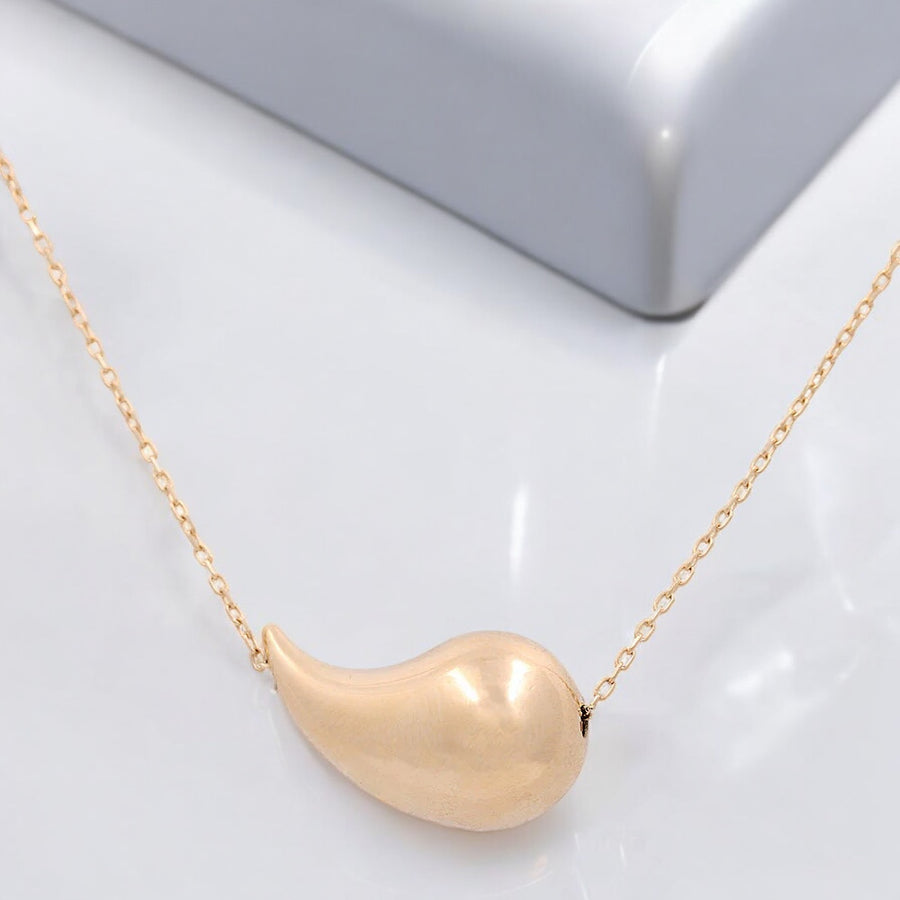 The Miral Jewelry 14K Yellow Gold Women's Fashion Small Drop Pendant Necklace rests elegantly on a white surface.